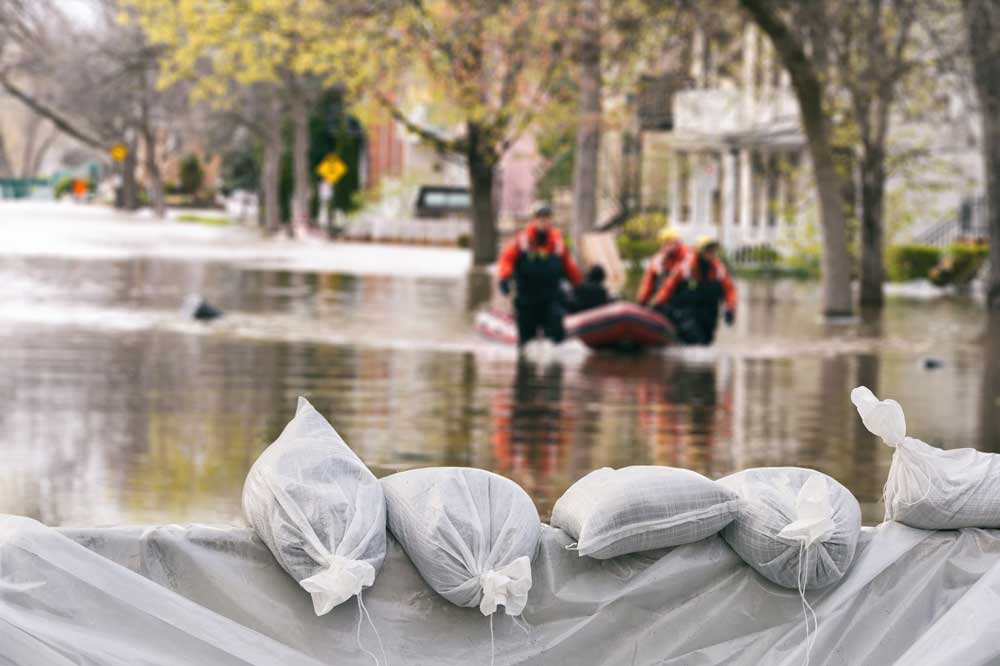 sandbags in front of flooded street with rescue boat