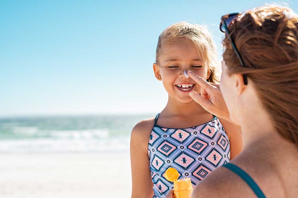 woman applying sunscreen to little girl nose