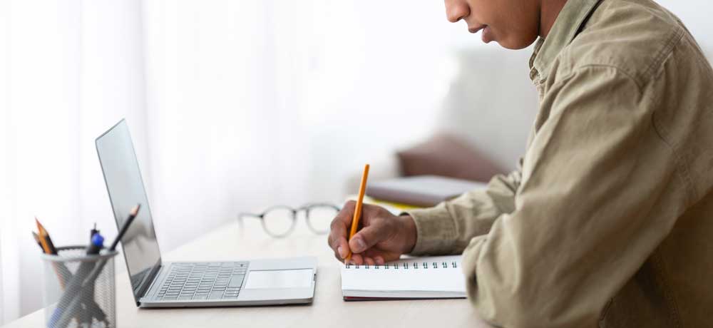 person with notebook open in front of computer